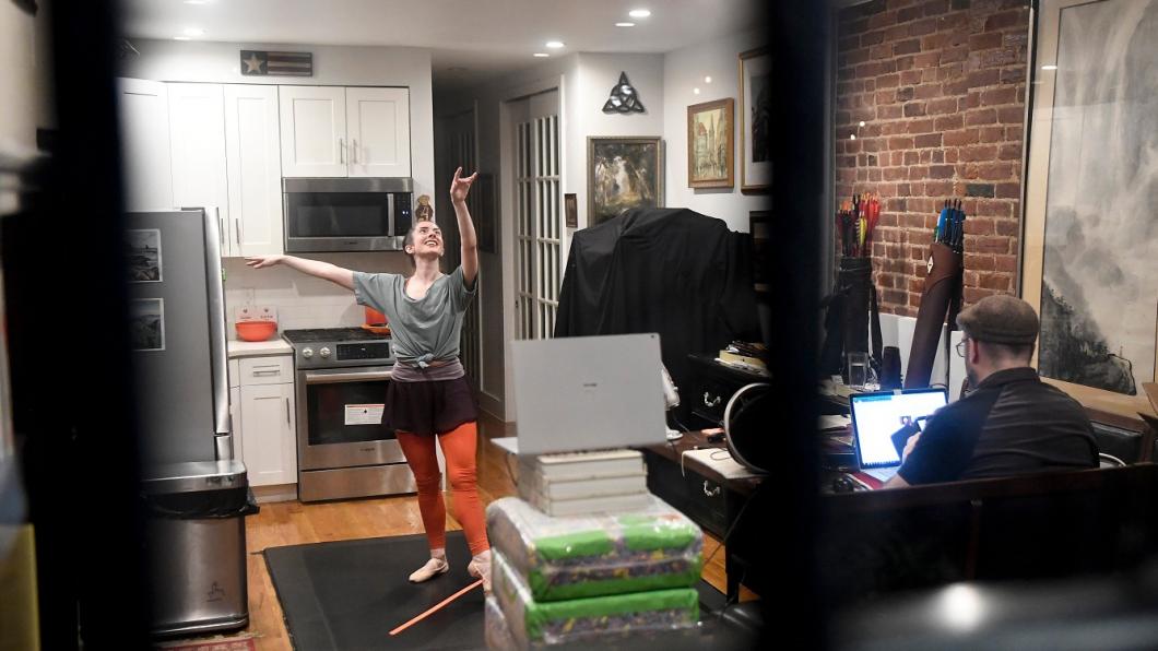 Woman doing ballet in kitchen in front of laptop